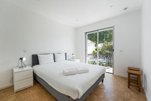 a white bedroom with a large bed and a window at Family Flat Near Porto in Rio Tinto