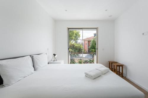 a white bedroom with a white bed and a window at Family Flat Near Porto in Rio Tinto