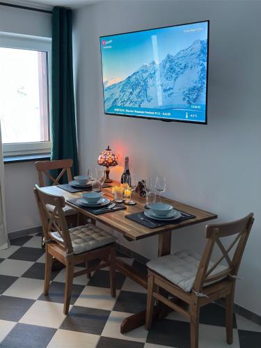 a dining room table with chairs and a television on the wall at Alpenfels Zwieselstein in Sölden