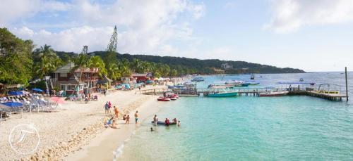 a group of people on a beach next to the water at Fosters West Bay Resort in West Bay