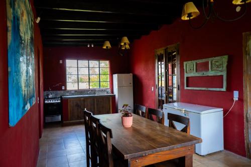 cocina con mesa de madera y paredes rojas en Casa Quinta la PAVA GRADE, en Chascomús