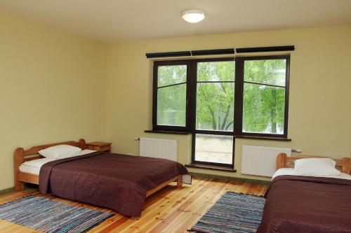 a bedroom with two beds and a large window at LVM tūrisma un atpūtas centrs "Ezernieki" in Meirāni