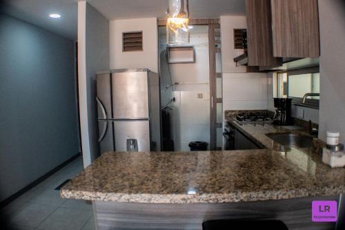 a kitchen with a granite counter top and a refrigerator at Apartamento Lujoso y Nuevo en Milán in Manizales