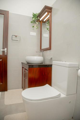 a bathroom with a white toilet and a sink at Villa White Elephant in Hikkaduwa
