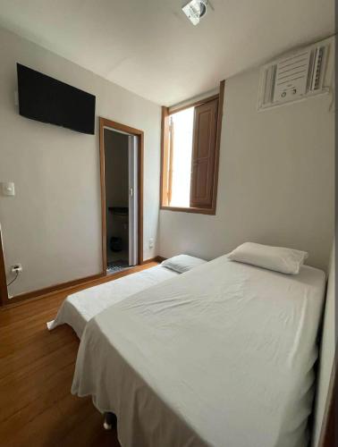 a bedroom with two white beds and a window at Suíte 302 - Pousada no Centro do Rio in Rio de Janeiro