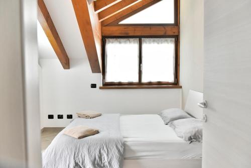 2 łóżka w białym pokoju z oknem w obiekcie La Pieve Apartments w mieście San Lorenzo in Banale