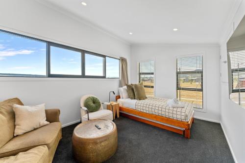 ein Wohnzimmer mit einem Bett, einem Sofa und Fenstern in der Unterkunft Puna Rise - Taupo Holiday Home in Taupo