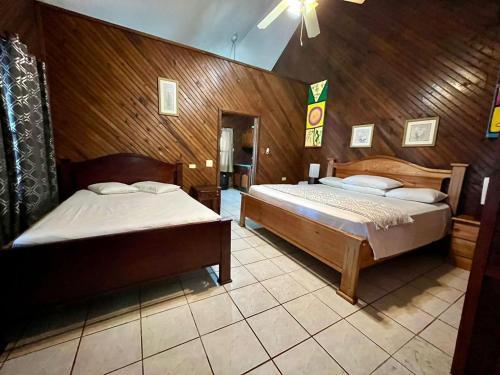 two beds in a room with wooden walls at Fosters West Bay Resort in West Bay