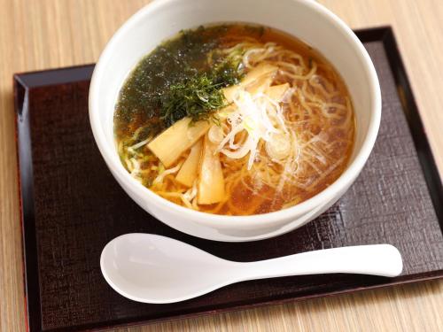 a bowl of soup on a plate with a spoon at Dormy Inn Express Mikawaanjo in Anjo