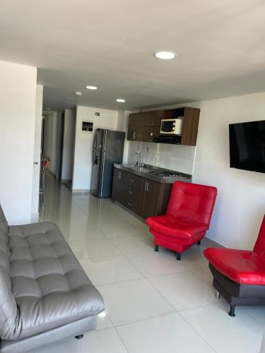 a living room with a couch and two red chairs at Ivanna Jumar ApartaHotel in Medellín