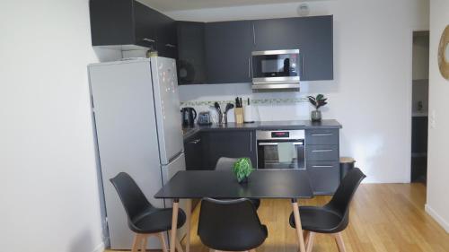 une cuisine avec une table, des chaises et un réfrigérateur dans l'établissement Le Cocon lumineux à 20mn de Paris et Orly, à Vigneux-sur-Seine