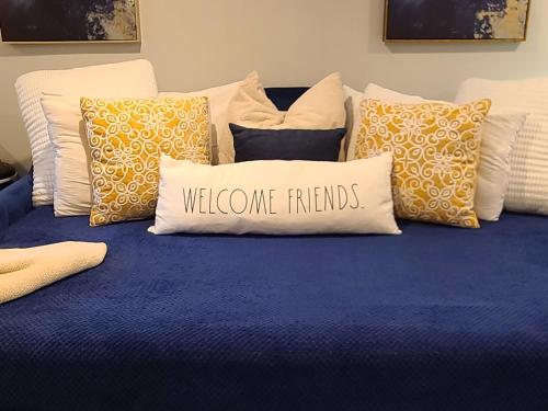a blue bed with pillows with a welcome friends pillow at Beautiful Basement Suite & Outdoor Oasis in Washington, D.C.