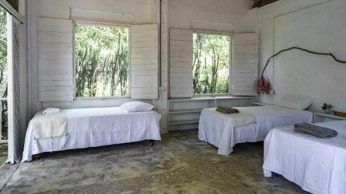 two beds in a room with two windows at Hotel Fuerte Mayal in Isla Fuerte