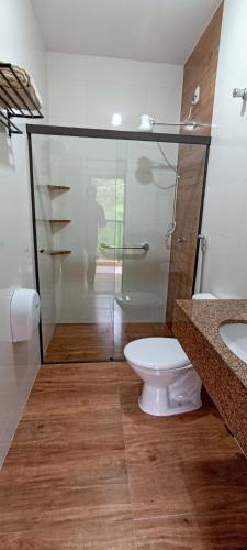 a bathroom with a toilet and a glass shower at Pousada Alejandro in Cunha