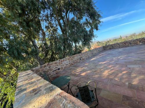 a stone retaining wall with two chairs and trees at Pietra Rossa in Chios