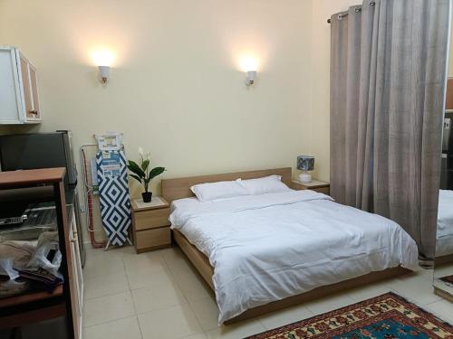 a bedroom with a white bed and a television at Khalifa A studio Room 13-6 in Abu Dhabi
