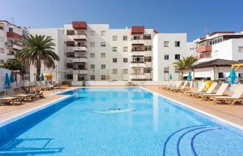 una grande piscina con sedie e edifici di Endless Summer Suite - swimming pool - AC ad Adeje