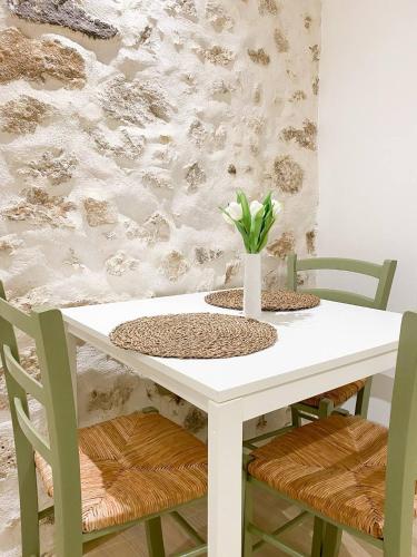 une table blanche avec des chaises et un vase avec des fleurs. dans l'établissement Logement entier appartement Antibes, France, à Antibes