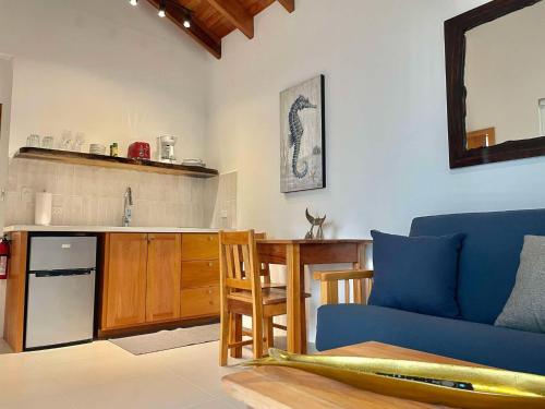 a living room with a couch and a table and a kitchen at Weezie's Ocean Front Hotel and Garden Cottages in Caye Caulker
