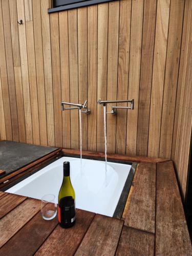a bottle of wine and a glass in a bath tub at Escape to Riverslea in Wanaka