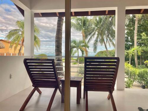 two chairs and a table in front of a window at Weezie's Ocean Front Hotel and Garden Cottages in Caye Caulker
