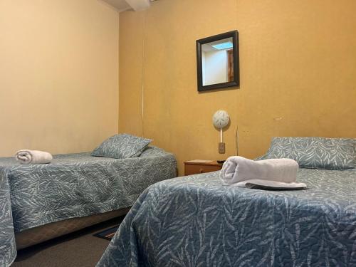 a room with two beds and a mirror on the wall at Hostal Don Guillermo in Puerto Natales