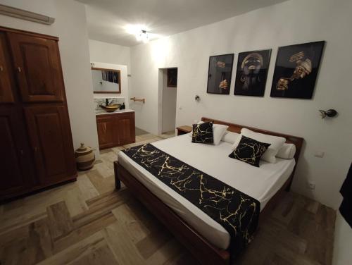a bedroom with a large bed with black and white pillows at Campement Houefa in Ndangane