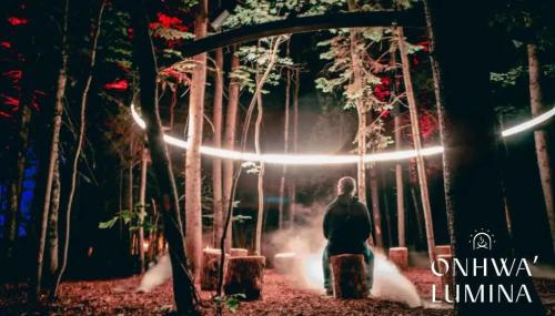 a man standing in a forest with lights at Les Suites des Chutes - La Royale in Boischâtel