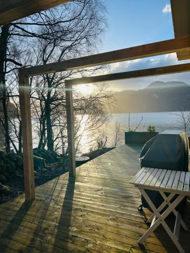 a wooden deck with a bench and a view of the water at Beautiful Beach line Cabin with sauna near Pulpit Rock in Forsand