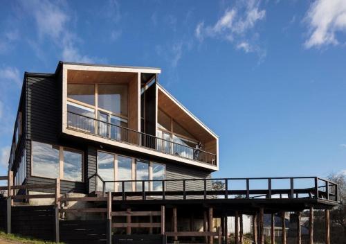 a house with a large deck and glass windows at Hotel Arrebol in Castro