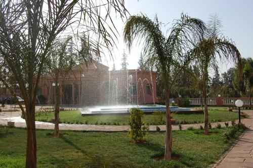 a fountain in a park in front of a building at Hotel Dar Eddaya in Khemisset