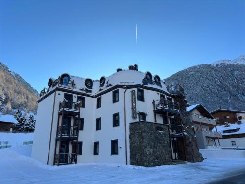a building in the snow with mountains in the background at Alpenfels Zwieselstein in Sölden