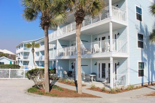 a large white building with palm trees in front of it at Summerspell Condominum in Destin
