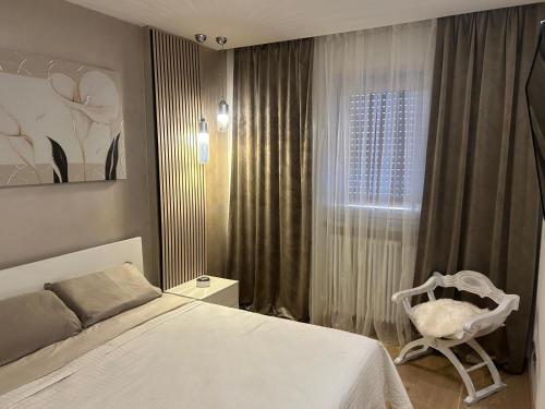 a bedroom with a bed and a chair next to a window at Maison Sofia in Aosta
