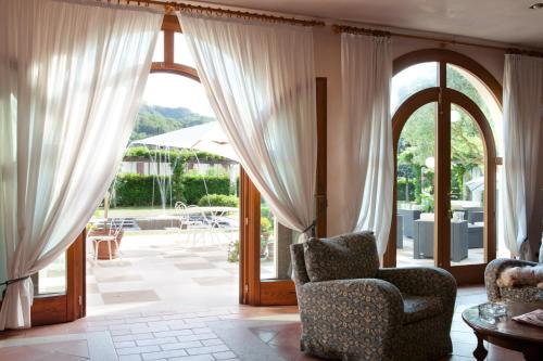 a living room with curtains and a chair and a patio at Hotel Villaguarda Prosecco Area in Follina