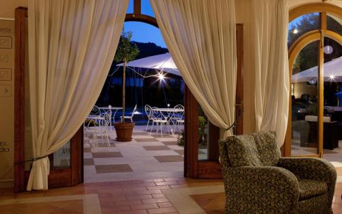 a room with curtains and a chair and tables at Hotel Villaguarda Prosecco Area in Follina