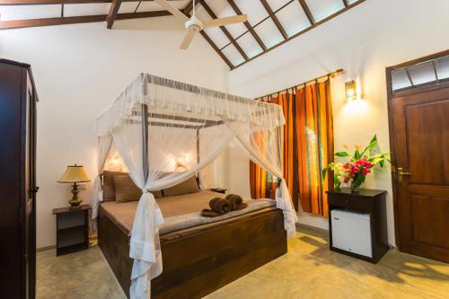 ein Schlafzimmer mit einem Himmelbett in einem Zimmer in der Unterkunft Forcus Cabanas in Arugam Bay