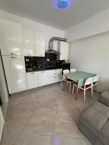a kitchen with white cabinets and a table and a table and chairs at Gjiri i Lalzit Lura 3 Apartment Toni in Draç
