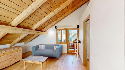 a living room with a blue couch and wooden ceilings at Chalet Rominger-Surlej in Surlej