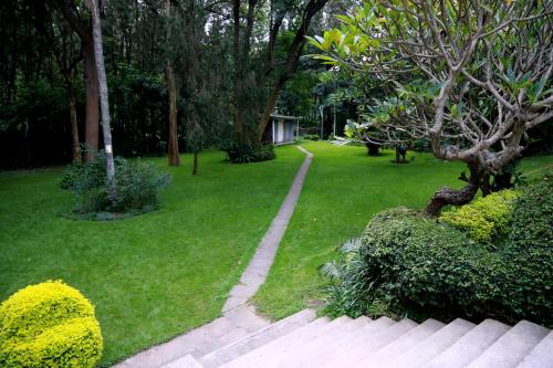 a garden with a path in the grass and trees at Equator Hotel in Arusha
