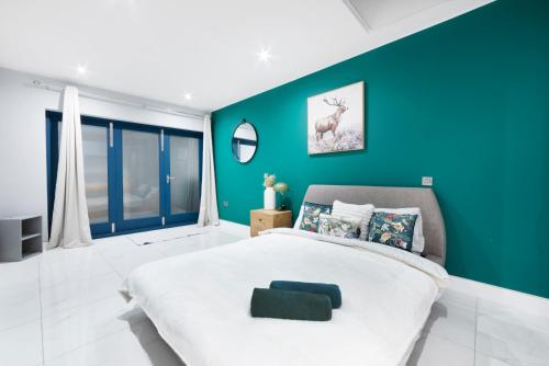 een slaapkamer met een groot bed en een blauwe muur bij High Ceiling Modern Apartment Heart of Central London in Londen