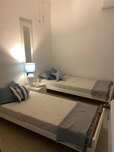two beds in a room with a lamp and a mirror at Appartamento vista mare Capo Falcone in Stintino