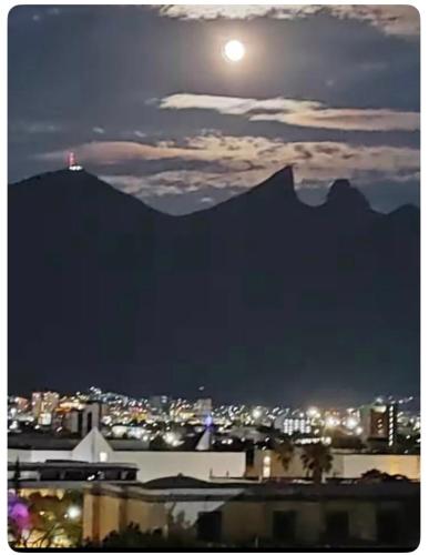 a view of a city at night with the moon at Lux 2 bedroom apartment, swimming pool, gym and free parking spot in Macro Plaza area in Monterrey