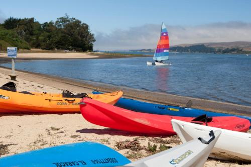 a group of kayaks on the beach with a sail boat at Tomales Bay Lodge and Marina Inc in Inverness