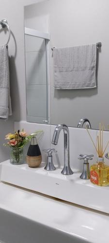 a bathroom sink with a mirror and flowers on it at Chalé Da Bia in Cananéia