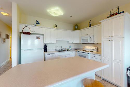 a kitchen with white cabinets and a white refrigerator at Peace on the sound, fun on the Beach in Indian Beach