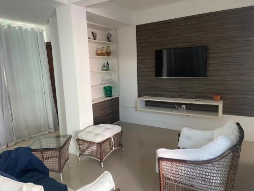 ein Wohnzimmer mit einem Fernseher an der Wand in der Unterkunft Praia do Flamengo 150m da praia Casa Ballalai in Salvador