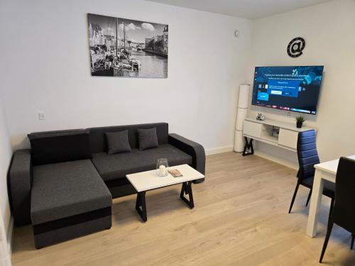 a living room with a black couch and a tv at 4 værelses lejlighed i Vejle in Vejle