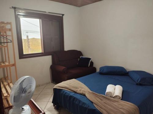 a bedroom with a bed and a fan and a window at Sobrado a Beira Mar in Rio Grande