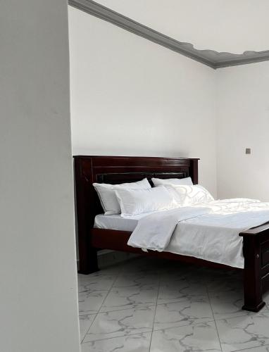 a bed with white sheets and pillows in a room at Dutus Hotel Entebbe in Wakiso